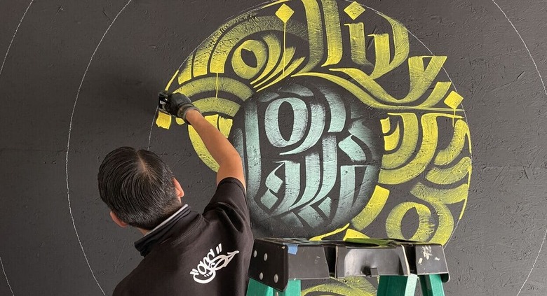 Zak Perez painting a mural at Progress on Main