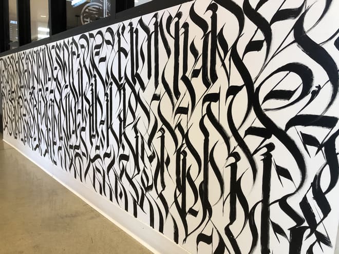 Defer mural at Rodeo 39 in black paint on a white wall