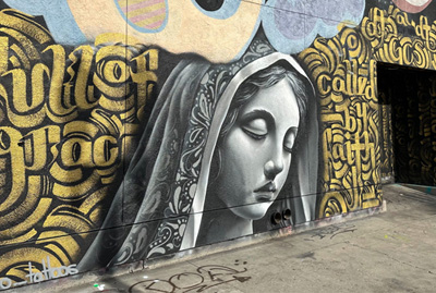 Mural with gold lettering and a portrait of Mary by Zak Perez and Panchito