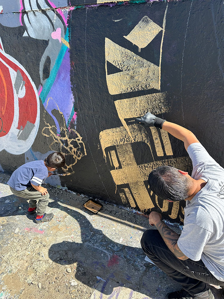 Zak Perez painting a mandala mural live during an event at the Graff Lab with his son painting next to him